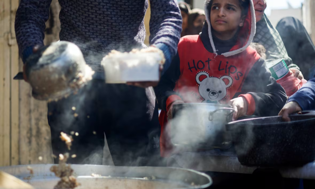 Palestinian children wait to receive food cooked at a charity kitchen, in Rafah on Tuesday. Aid groups in Gaza say the number of trucks bringing in food has been falling. (Mohammed Salem/Reuters)