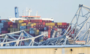 The steel frame of the Francis Scott Key Bridge sits on top of a container ship after the bridge collapsed on Tuesday.