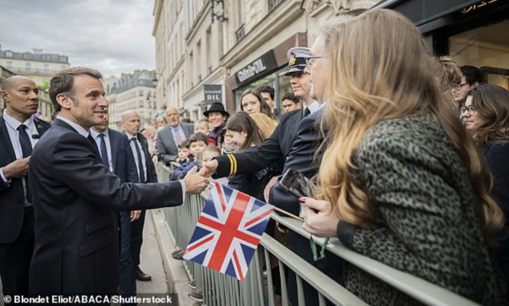 French President Emmanuel Macron shakes hands to onlookers outside the Elysee Palace today